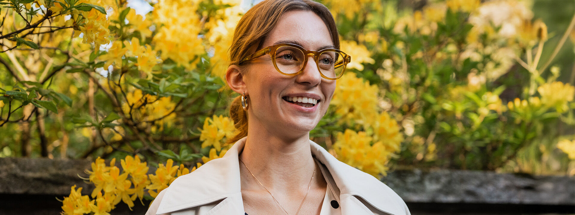 Silm&auml;lasip&auml;inen nainen ulkona iloisesti hymyillen